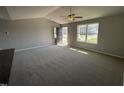 Bright living room with neutral walls, vaulted ceiling, ceiling fan and large windows, offering a welcoming space at 57 Faucette Dr, Selma, NC 27576
