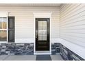 Close-up of a modern front door with decorative glass, flanked by stone accents and a sleek black shutter at 192 Springhill Ln, Garner, NC 27529