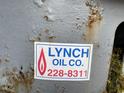 Close-up of a sticker indicating Lynch Oil Co. with a phone number on a metallic surface at 3115 Woods Chapel Rd, Graham, NC 27253