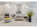 Modern white kitchen with stainless steel appliances, marble backsplash, and pendant lighting at 328 Conner Ridge Rd, Efland, NC 27243