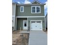 Charming two-story home featuring green siding, white trim, a one-car garage, and a neatly poured concrete driveway at 46 Shay St, Angier, NC 27501