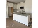 A modern kitchen features a granite island with a sink, complemented by white cabinets and stainless steel appliances at 46 Shay St, Angier, NC 27501