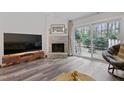 Bright living room featuring a brick fireplace, sliding glass doors, and modern wood flooring at 5840 Branchwood Rd, Raleigh, NC 27609