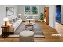 Bright living room featuring hardwood floors, stylish striped rug, white modern furniture, and view to the outside at 1004 Carlisle St, Raleigh, NC 27610