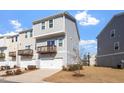 Stylish two-story townhome featuring a garage and a balcony overlooking a landscaped yard at 1018 Salt Glaze Ln, Cary, NC 27519
