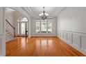 Spacious dining room with wood floors, wainscoting, crown molding, and a modern chandelier at 109 Coffeeberry Ct, Garner, NC 27529