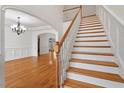 Bright living room featuring hardwood floors, a staircase with wood and white accents, and an archway at 109 Coffeeberry Ct, Garner, NC 27529
