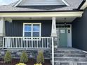 Inviting covered front porch with stone base and green front door at 143 Prency Ln, Middlesex, NC 27557