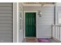 The front door is green with a window to the side and welcome mats in front of the door at 2020 University Woods Rd # 203, Raleigh, NC 27603