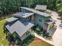 Aerial view of a green home with solar panels, attached garage and lush, mature landscaping at 295 Cedar Rock Trl, Fuquay Varina, NC 27526