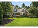 Inviting brick home with well-maintained lawn, mature trees, and manicured landscaping at 5708 Creekfall Ln, Fuquay Varina, NC 27526