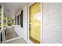 Close-up of a bright yellow front door framed by white brick and black shutters at 11254 Hwy Nc 50, Benson, NC 27504