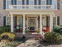 Inviting front porch features brick flooring, classic columns, and cozy seating, creating a welcoming entrance at 12344 Canolder St, Raleigh, NC 27614