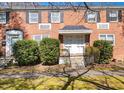 Brick two-story townhouse with black shutters and manicured landscaping with inviting covered entrance at 1603 Sutton Dr, Raleigh, NC 27605