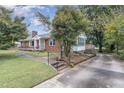 Lovely property featuring a brick home, mature trees, and a well-maintained driveway with backyard access at 1807 S Mebane St, Burlington, NC 27215