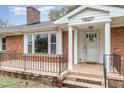 Inviting home entrance with a brick facade, white columns, and a tiled front porch at 1807 S Mebane St, Burlington, NC 27215