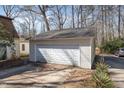 View of the detached garage offering ample space with a multi-panel door in a serene backyard at 214 Woodcrest Ave, Smithfield, NC 27577