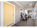 Inviting front porch features a bright yellow door, wood furniture, stylish decor and overhead lighting at 2715 Edmund St, Durham, NC 27705