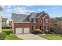 Charming two-story brick home with a well-manicured lawn, attached two-car garage, and mature landscaping at 3208 Marblewood Ct, Raleigh, NC 27604