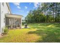 Spacious backyard featuring lush green grass, a screened in porch, and a grill on a concrete patio at 340 Olde Liberty Dr, Youngsville, NC 27596