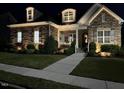 Beautiful exterior of a one-story home at night with stone accents and manicured lawn at 44 Ashwood Dr, Chapel Hill, NC 27516
