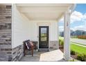 Inviting covered front porch with stone accents, seating, and view of neighborhood street at 52 Commons Cir, Clayton, NC 27520