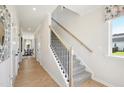 Bright hallway with hardwood floors, staircase, and view into adjacent dining room at 52 Commons Cir, Clayton, NC 27520