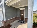 Inviting front entrance with a brown door, brick foundation, and a welcome mat at 52 Old Mill Road at 52 Commons Cir, Clayton, NC 27520
