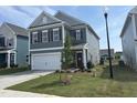 Charming two-story home with gray siding, white trim, a two-car garage, and a newly planted tree at 52 Commons Cir, Clayton, NC 27520