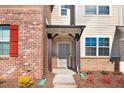 Detailed view of a townhome entrance with brick facade, dark wood support pillars, and manicured flower beds at 736 Wickham Ridge Rd, Apex, NC 27539