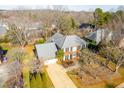 Aerial view of a two-story brick home surrounded by mature trees and lush landscaping at 107 Longbrook Dr, Elon, NC 27244