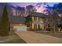Charming brick home at twilight, featuring a spacious driveway and attached two-car garage at 107 Longbrook Dr, Elon, NC 27244