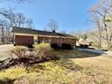 Back view of a brick home with a well-kept lawn and mature shrubbery, situated on a spacious lot at 2118 N Woodland Rd, Henderson, NC 27536
