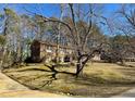 Brick home with mature trees on a sloping lot, presenting a classic and established appearance at 2118 N Woodland Rd, Henderson, NC 27536