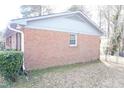 Brick exterior view showcasing the side of the home with a window and greenery at 2918 Kanewood Dr, Durham, NC 27707