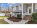 A charming home's entrance with brick stairs, white railings and trim, with gray siding and well-maintained landscaping at 5412 Farley Dr, Raleigh, NC 27609