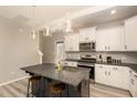 Open kitchen featuring white cabinets, stainless steel appliances, and an island with barstool seating at 5439 Ripplebrook Rd, Durham, NC 27712