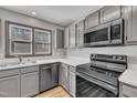 Well lit kitchen with stainless steel appliances and gray cabinets at 6036 Epping Forest Dr, Raleigh, NC 27613
