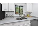 Modern kitchen with stainless steel sink, white cabinets, and countertops, with a window view at 689 Pine Ridge Pl, Raleigh, NC 27609