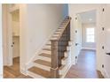 Elegant staircase with hardwood steps and a dark metal railing leading to the second floor at 75 Harvest View Way, Franklinton, NC 27525