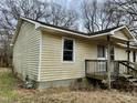 Side view of single story home with weathered siding, small porch and overgrown lawn at 750 David St, Henderson, NC 27536