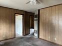 Unfurnished living room with wood paneled walls, ceiling fan, and doorway to adjacent room at 750 David St, Henderson, NC 27536