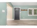 Inviting living room with stylish gray wood flooring, front door, and calming light green walls at 7722 Nc 27 W, Lillington, NC 27546