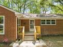 Inviting front porch with wooden railing, brick exterior, and security system sign at 1411 Rosewood St, Durham, NC 27701