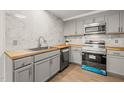 Updated kitchen showcasing wood countertops, grey cabinets, and stainless steel appliances at 1411 Rosewood St, Durham, NC 27701