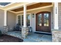 Charming front porch with stone accents, a wood ceiling, and a cozy seating area at 1520 Grand Willow Way, Raleigh, NC 27614