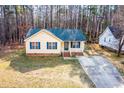 A yellow home with blue shutters on a large lot among the trees near a concrete driveway at 5748 Presentation St, Knightdale, NC 27545