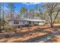 Ranch style home with metal roof and mature trees on a lot covered with pine needles at 723 Chelsea Dr, Sanford, NC 27332