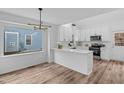 Modern white kitchen featuring stainless steel appliances, quartz countertops, and stylish lighting fixture at 107 Kingsmill Rd, Cary, NC 27511
