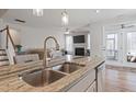 Granite island with a stainless steel sink and faucet in this kitchen with views of the living room at 201 Northview Dr, Middlesex, NC 27557